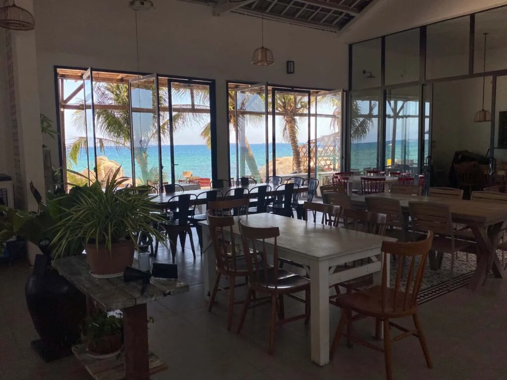 An airy ocean-view dining room framed by palms at Kim Anh Restaurant