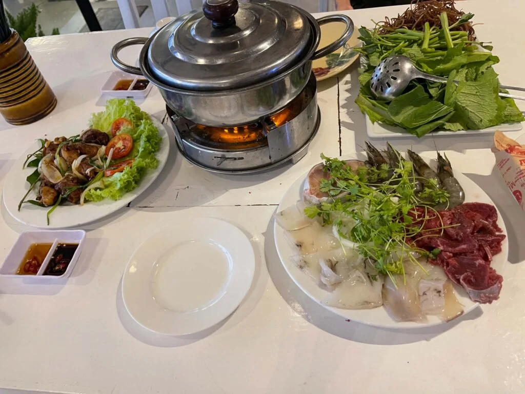A seafood hotpot simmering over a burner with fresh shrimp, squid and garden herbs